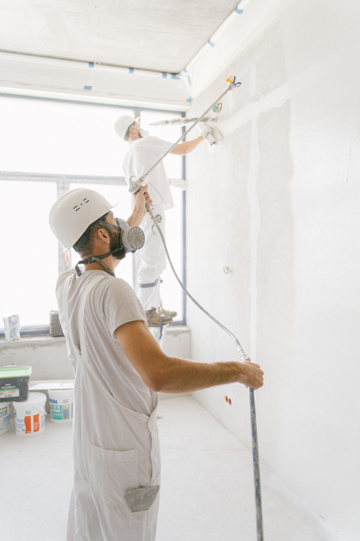 Maler arbeiten konzentriert an den Wänden eines hellen Innenraums.